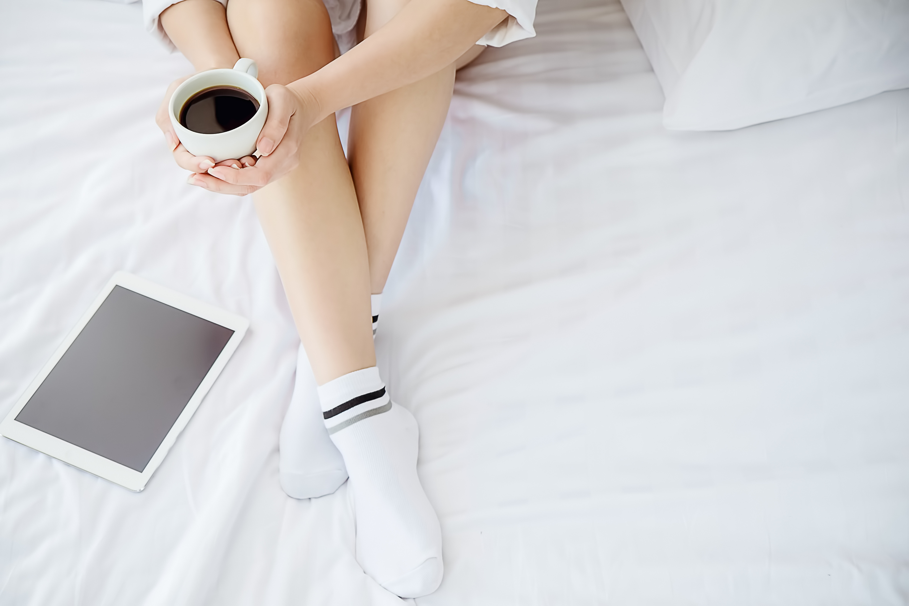 Woman with Tablet and Coffee in Bed